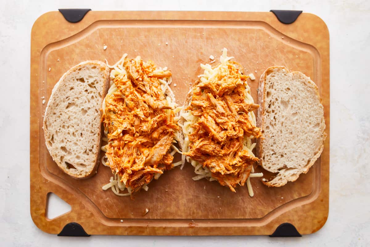 Slices of bread topped with shredded cheese and buffalo chicken.