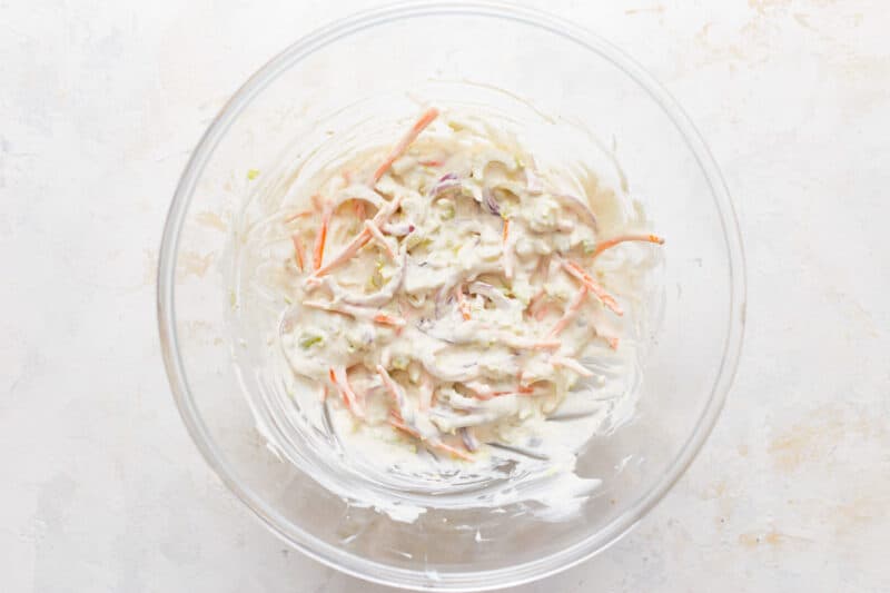 Coleslaw in a glass bowl on a white background.
