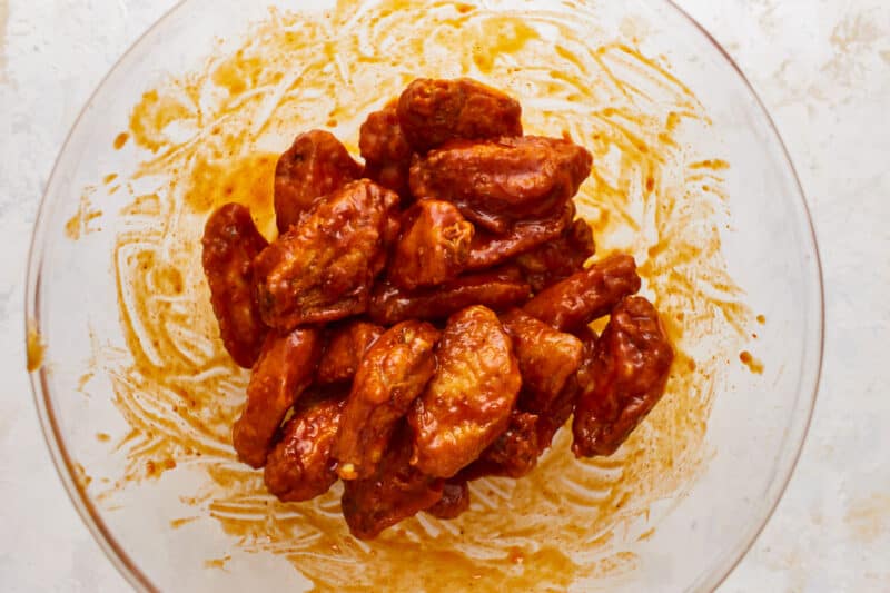 Chicken wings in a bowl with sauce.