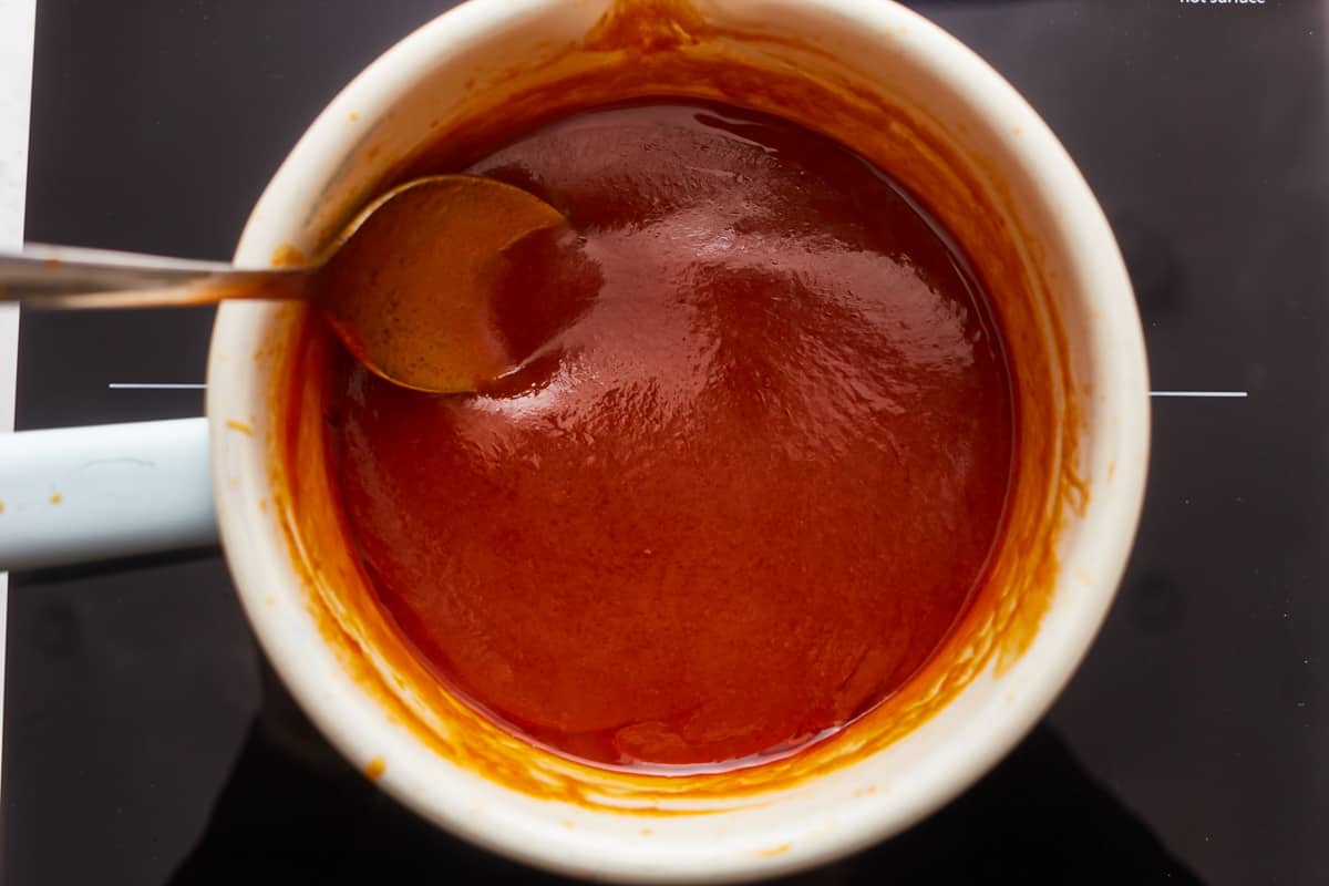 A cup of sauce with a spoon in it.