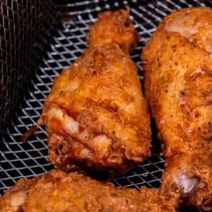 Fried chicken in a metal basket on a stovetop.