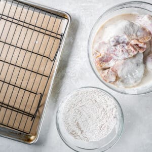 A baking sheet with chicken, flour, and other ingredients.