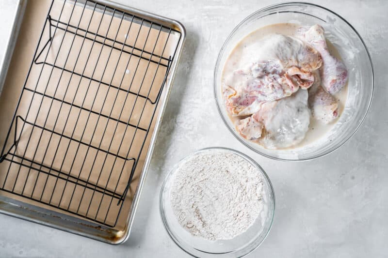 A baking sheet with chicken, flour, and other ingredients.