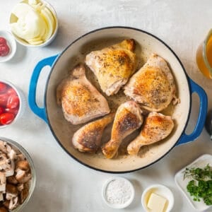 A pan with chicken, mushrooms and other ingredients on a white background.