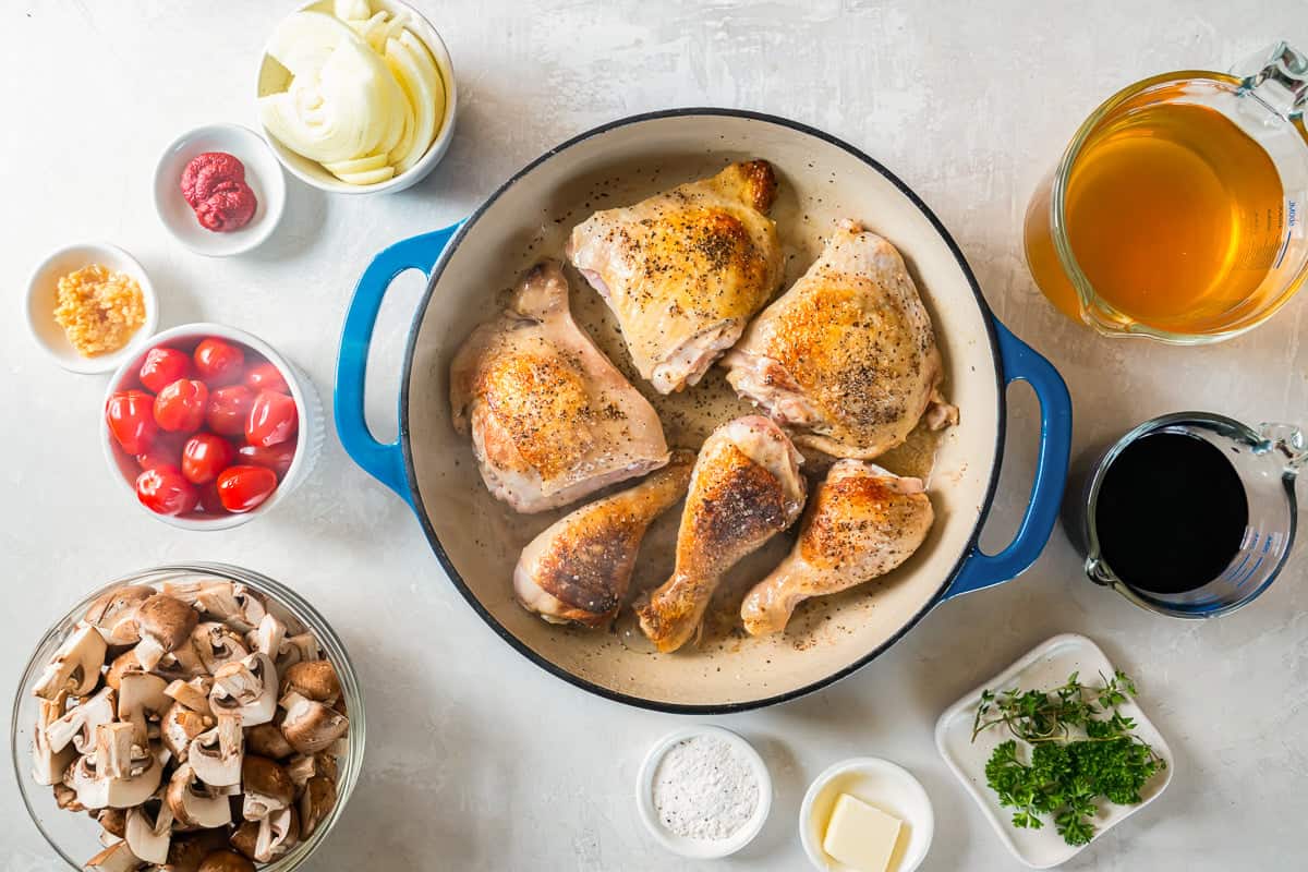 A pan with chicken, mushrooms and other ingredients on a white background.