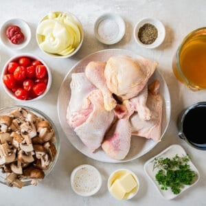 Chicken, mushrooms, tomatoes and other ingredients on a white background.