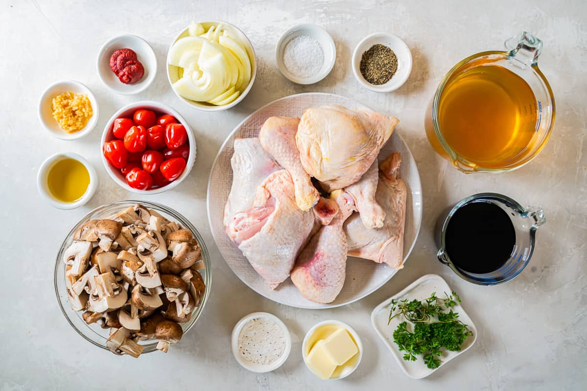 Chicken, mushrooms, tomatoes and other ingredients on a white background.