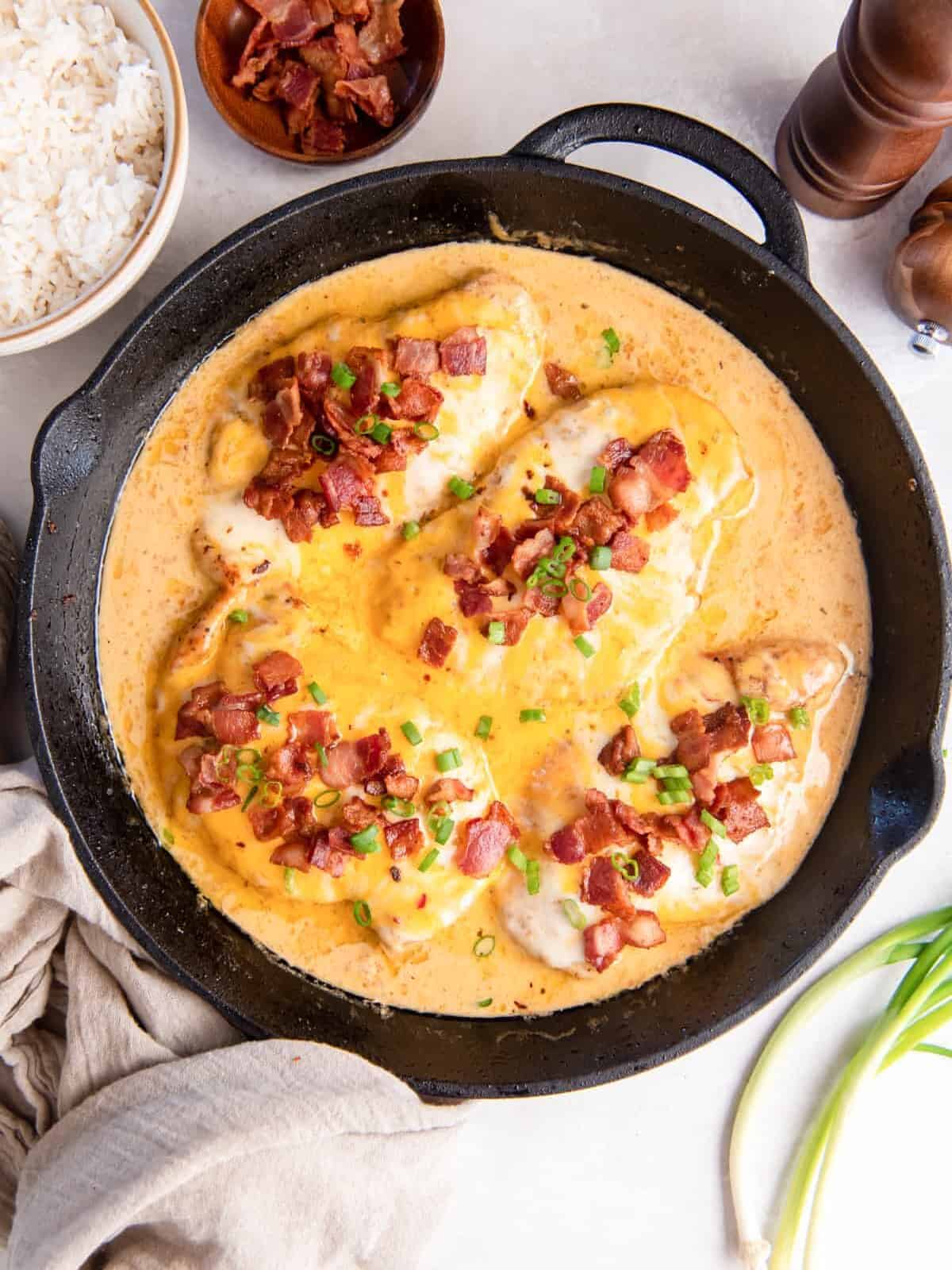overhead view of cheesy bacon ranch chicken in a cast iron skillet.