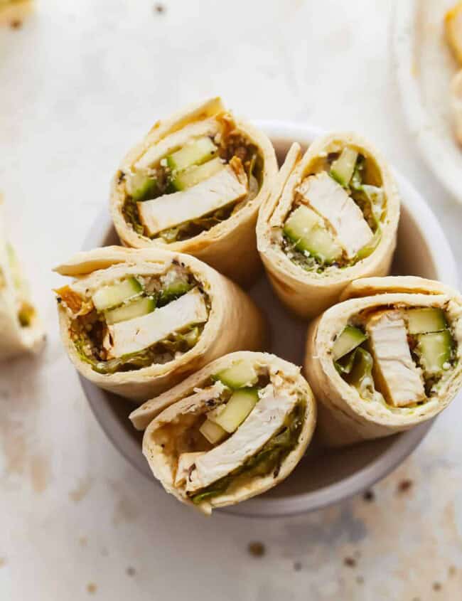 Chicken and cucumber wraps on a white plate.