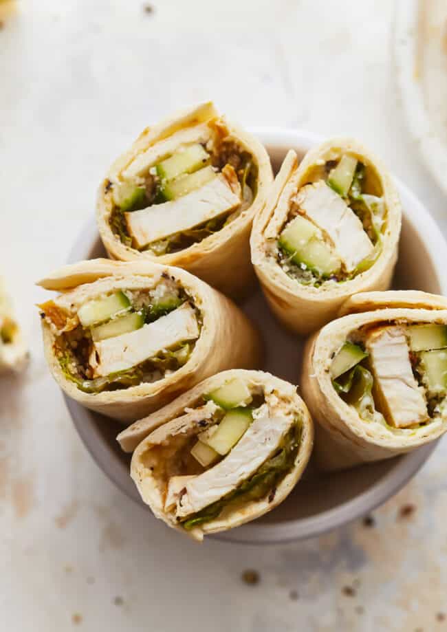 Chicken and cucumber wraps on a white plate.