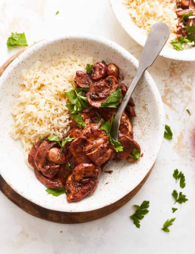 A bowl of rice and mushrooms in a white bowl.