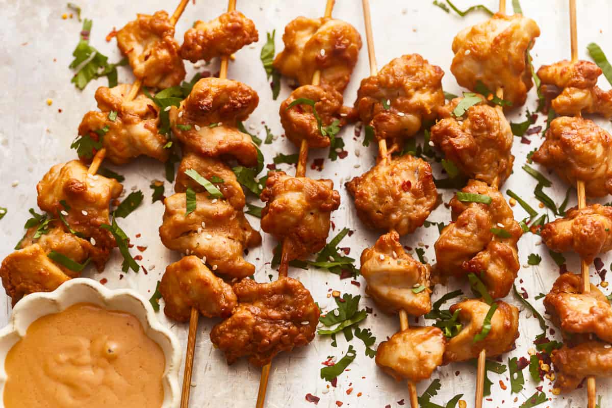 Chicken skewers with sauce on a tray.