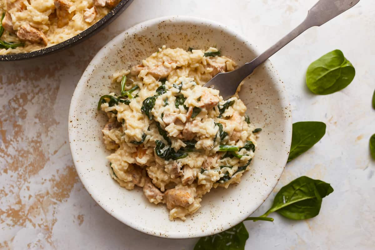 Risotto with spinach and chicken in a white bowl.