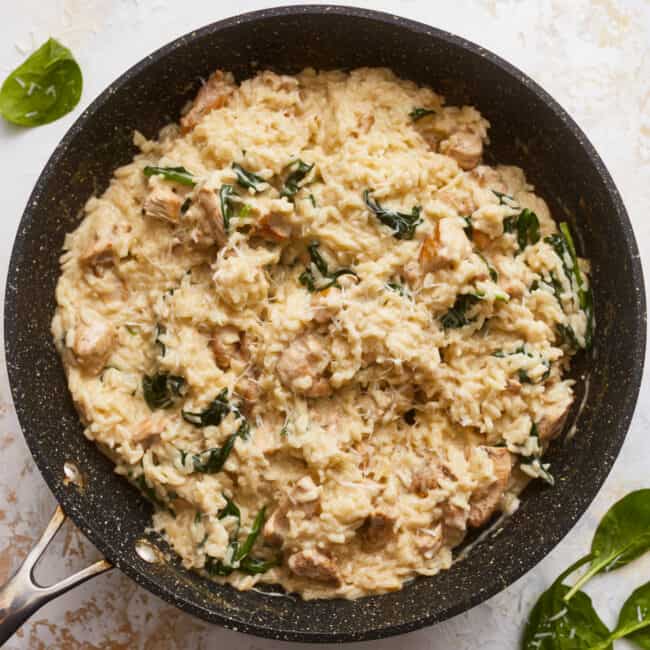Chicken and spinach in a skillet with a spatula.