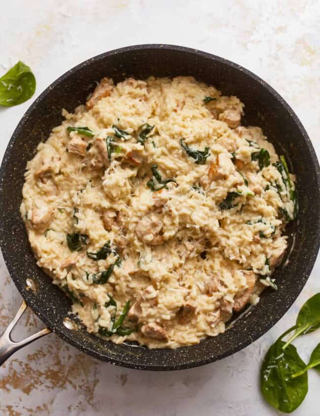 Chicken and spinach in a skillet with a spatula.