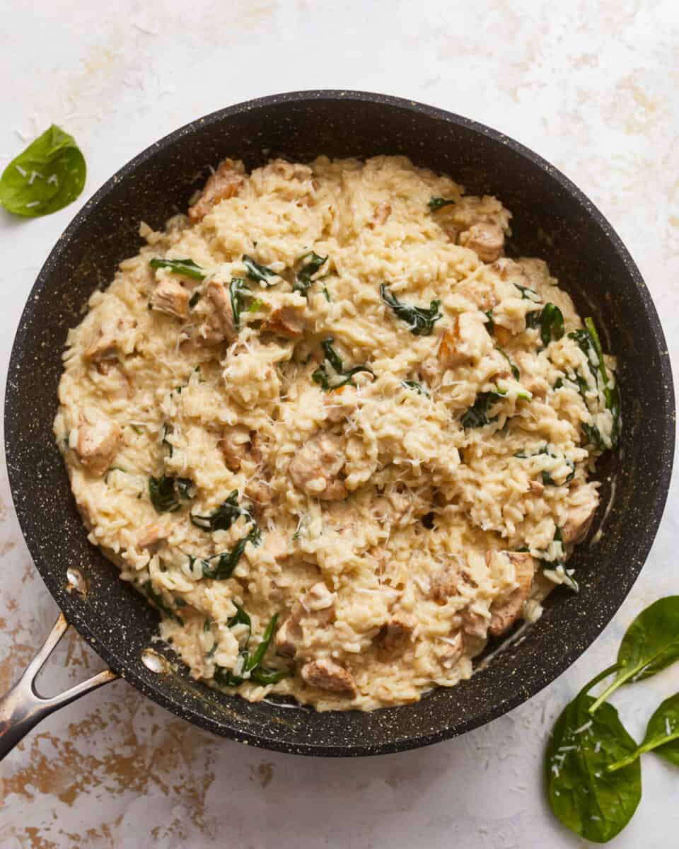 Chicken and spinach in a skillet with a spatula.