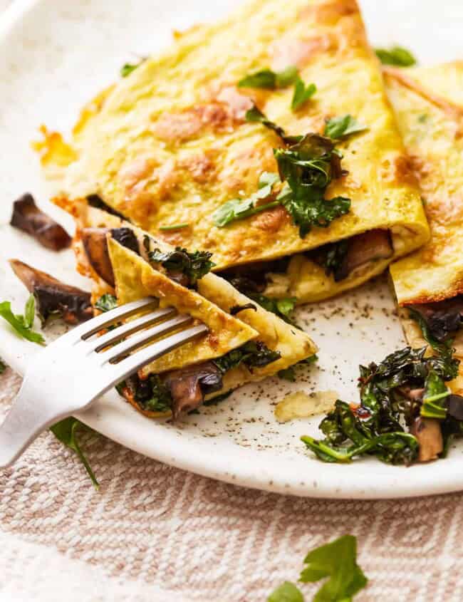 An omelet with mushrooms and spinach on a plate.