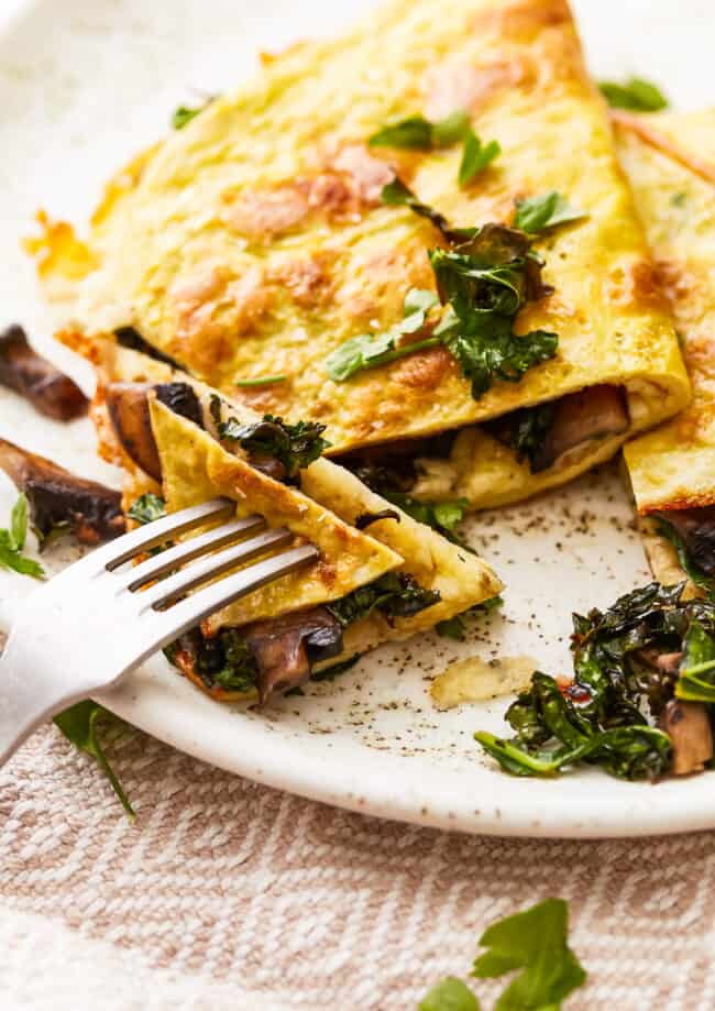 An omelet with mushrooms and spinach on a plate.