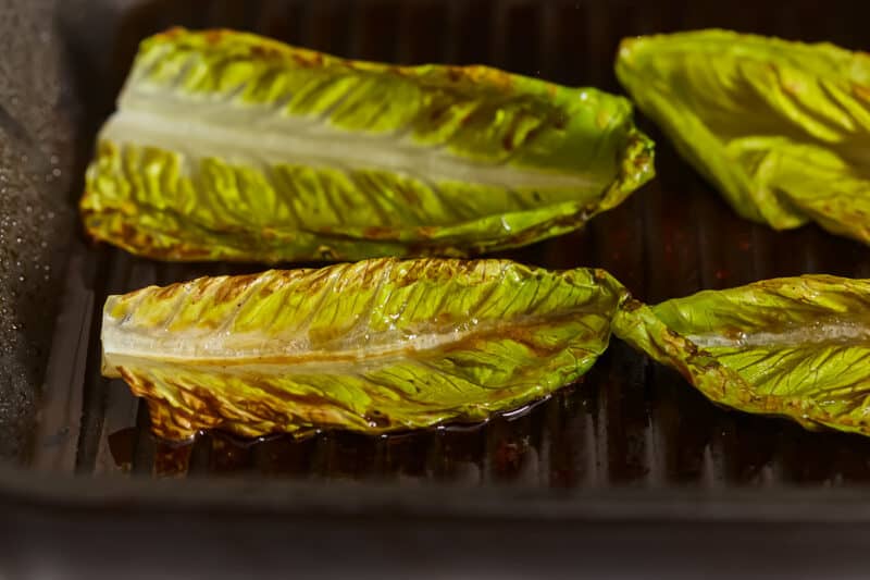 Grilled lettuce leaves in a frying pan.