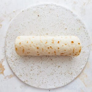 A roll of tortilla on a white plate.
