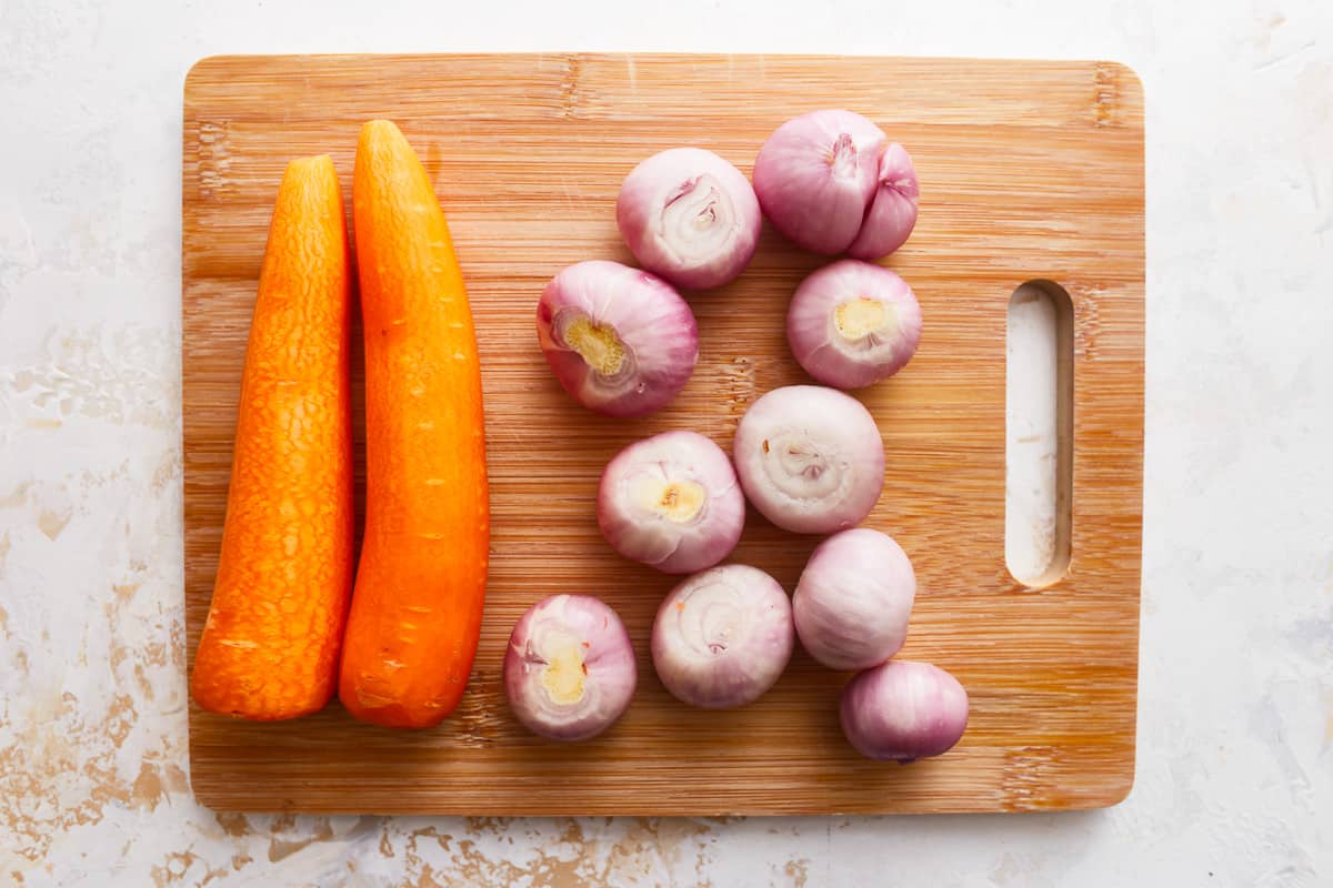 Carrots and onions on a cutting board.