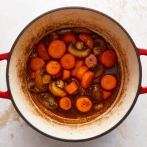 A pot filled with carrots and mushrooms.