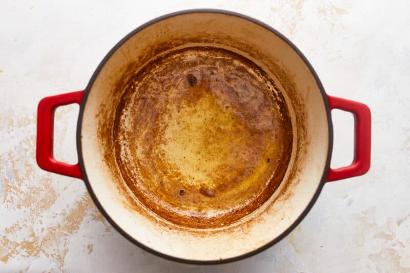 A pot filled with brown gravy on a white surface.