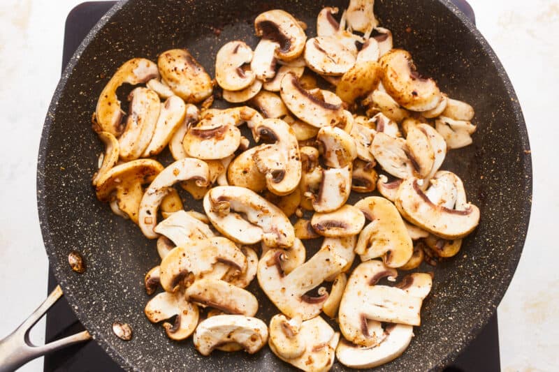 Mushrooms in a frying pan with a spatula.