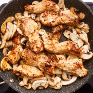 Chicken and mushrooms in a frying pan.