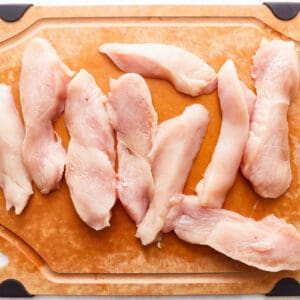 Chicken breasts on a cutting board on a white background.