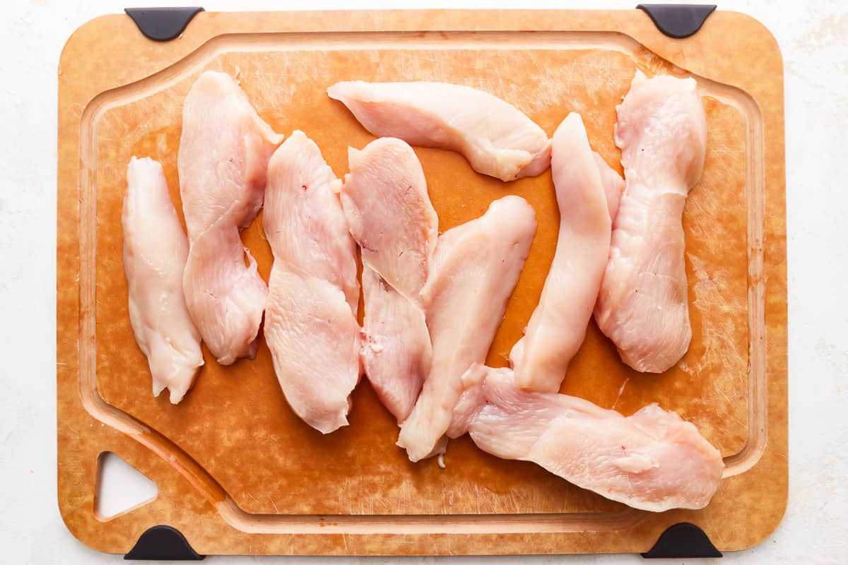 Chicken breasts on a cutting board on a white background.