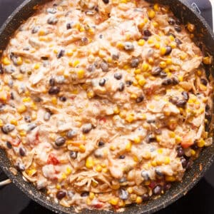 A skillet full of mexican chicken and corn.