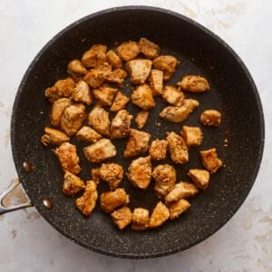 Fried chicken in a frying pan on a white background.