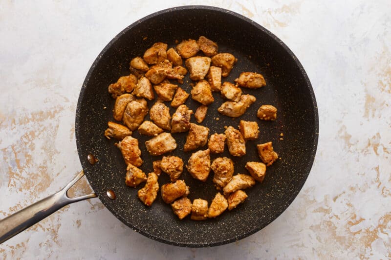 Fried chicken in a frying pan on a white background.