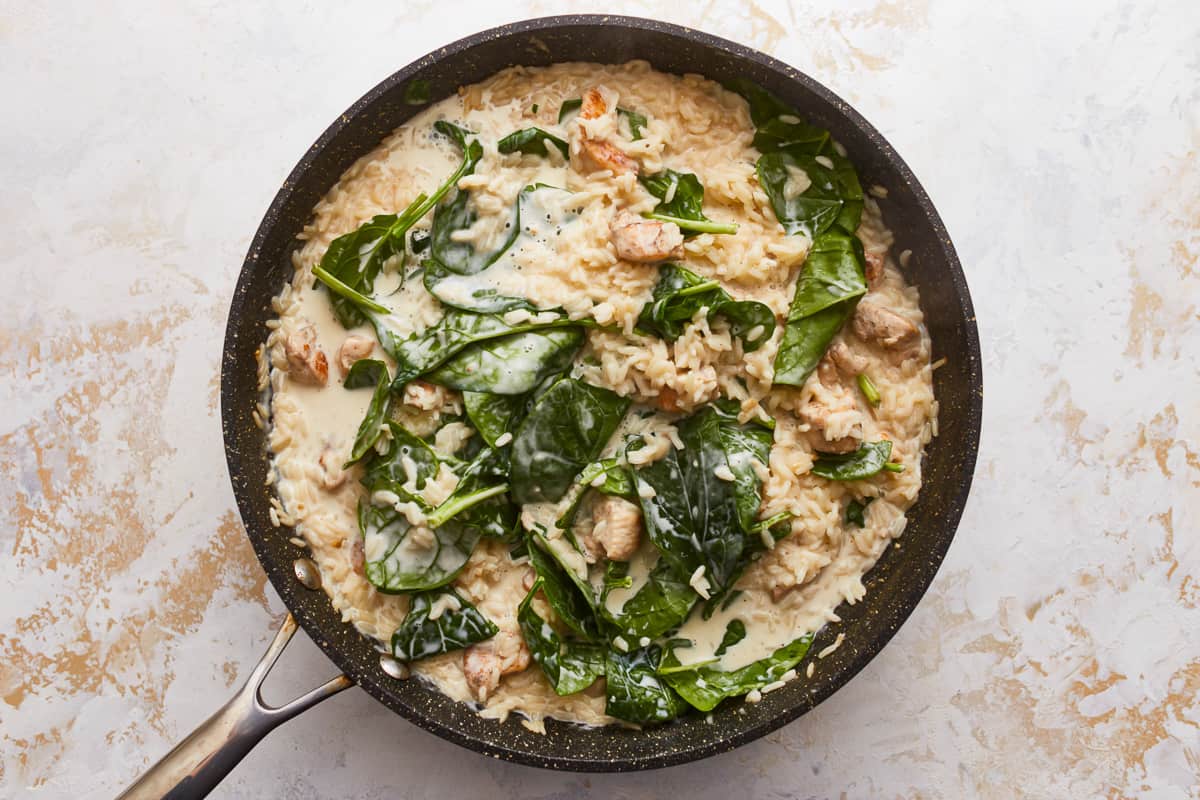 A skillet filled with rice and spinach.