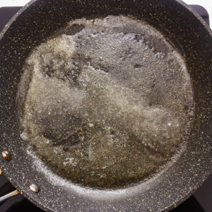 A frying pan filled with oil on a stove top.