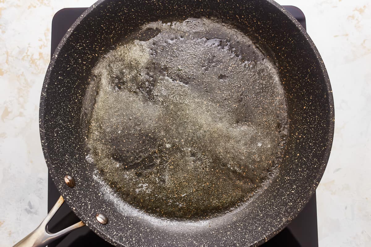 A frying pan filled with oil on a stove top.