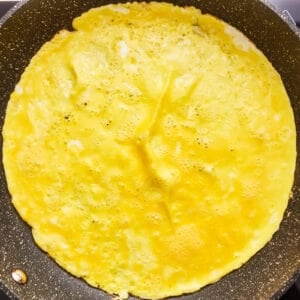 An omelet is being cooked in a frying pan.