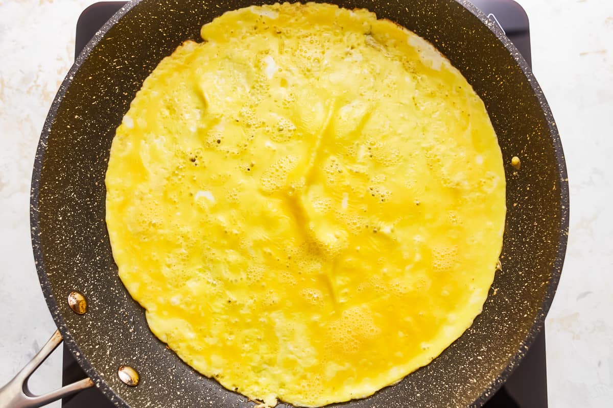 An omelet is being cooked in a frying pan.