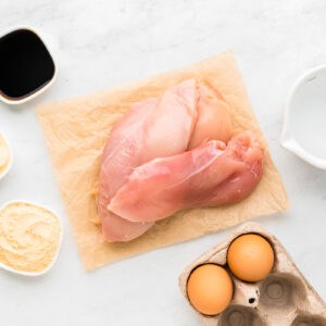 Chicken breast, eggs and other ingredients on a white background.