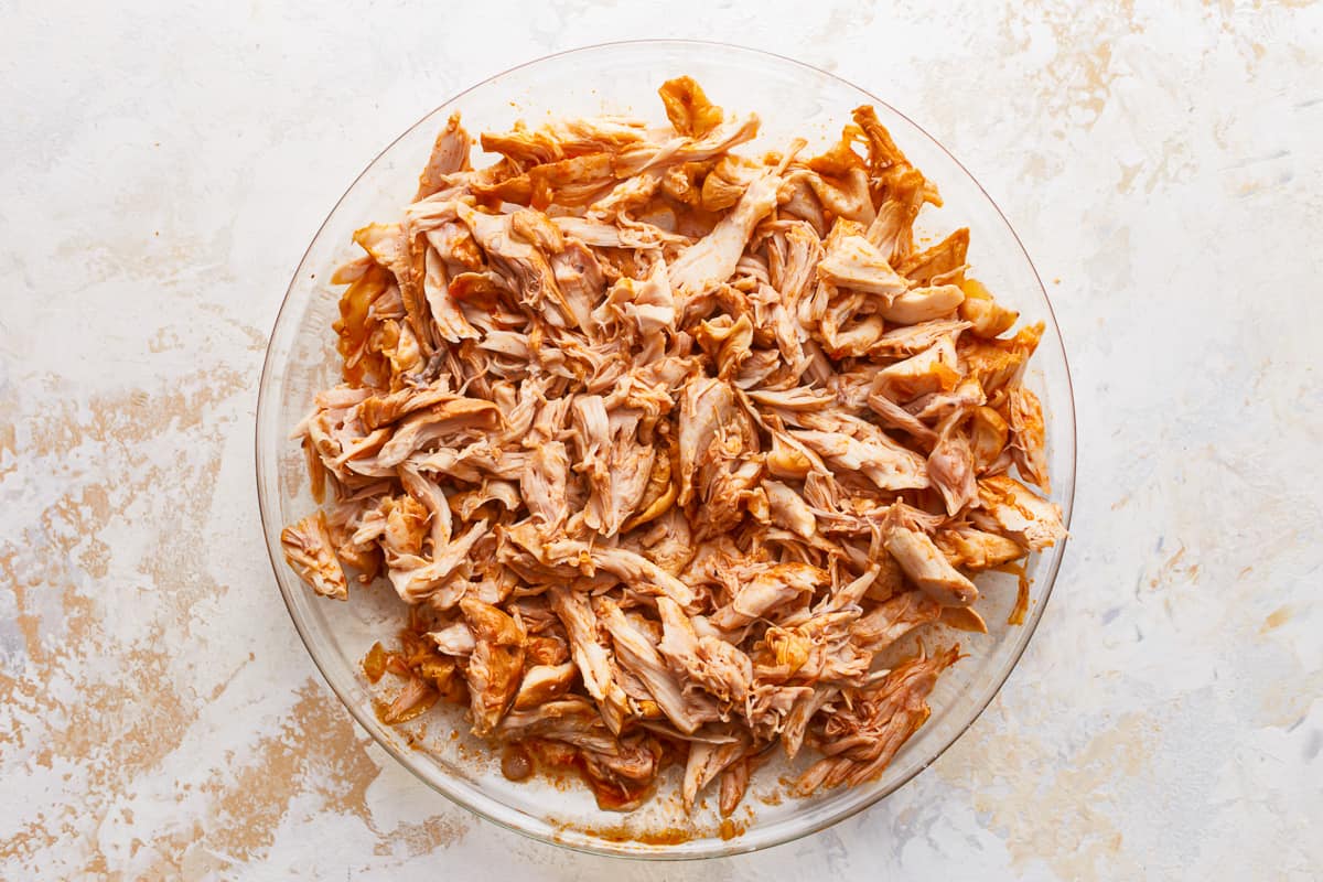 Shredded chicken in a glass dish on a white background.