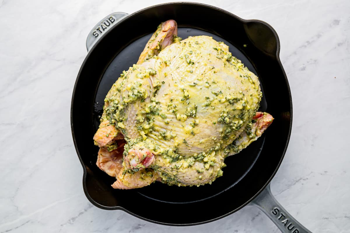 A chicken in a pan with pesto on it.