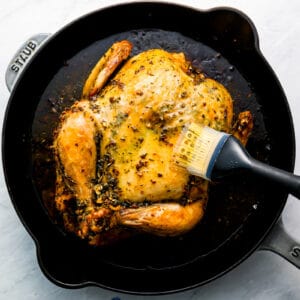 A person is slicing a chicken in a skillet.