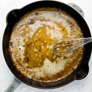 A skillet filled with oil and a whisk.