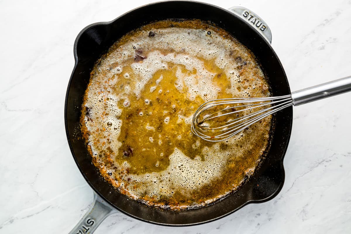 A skillet filled with oil and a whisk.