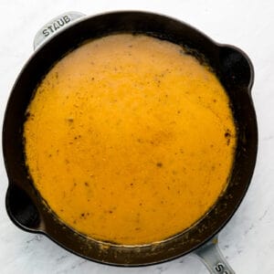 A cast iron skillet with a sauce in it.