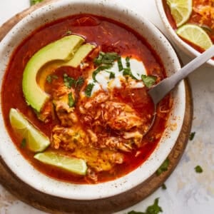 Two bowls of mexican chicken soup with avocado and lime.