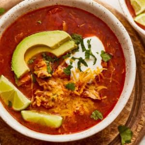 Two bowls of mexican chicken soup on a wooden board.