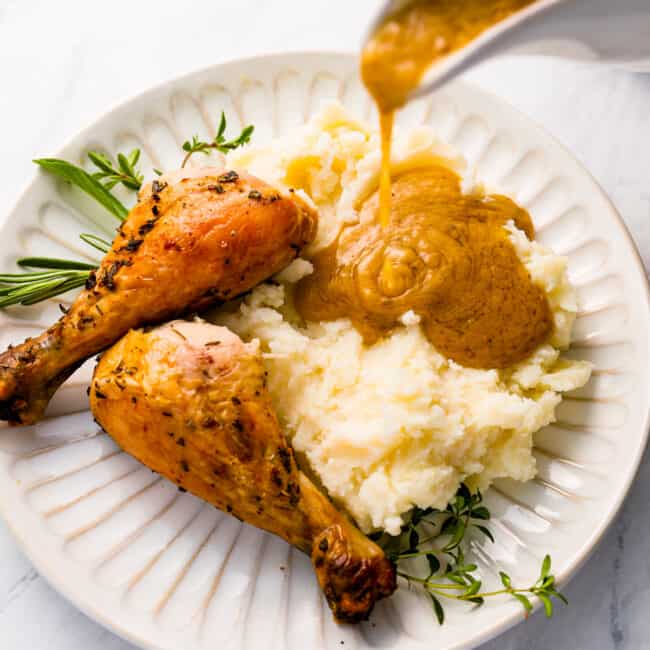 Gravy being poured over chicken and mashed potatoes.