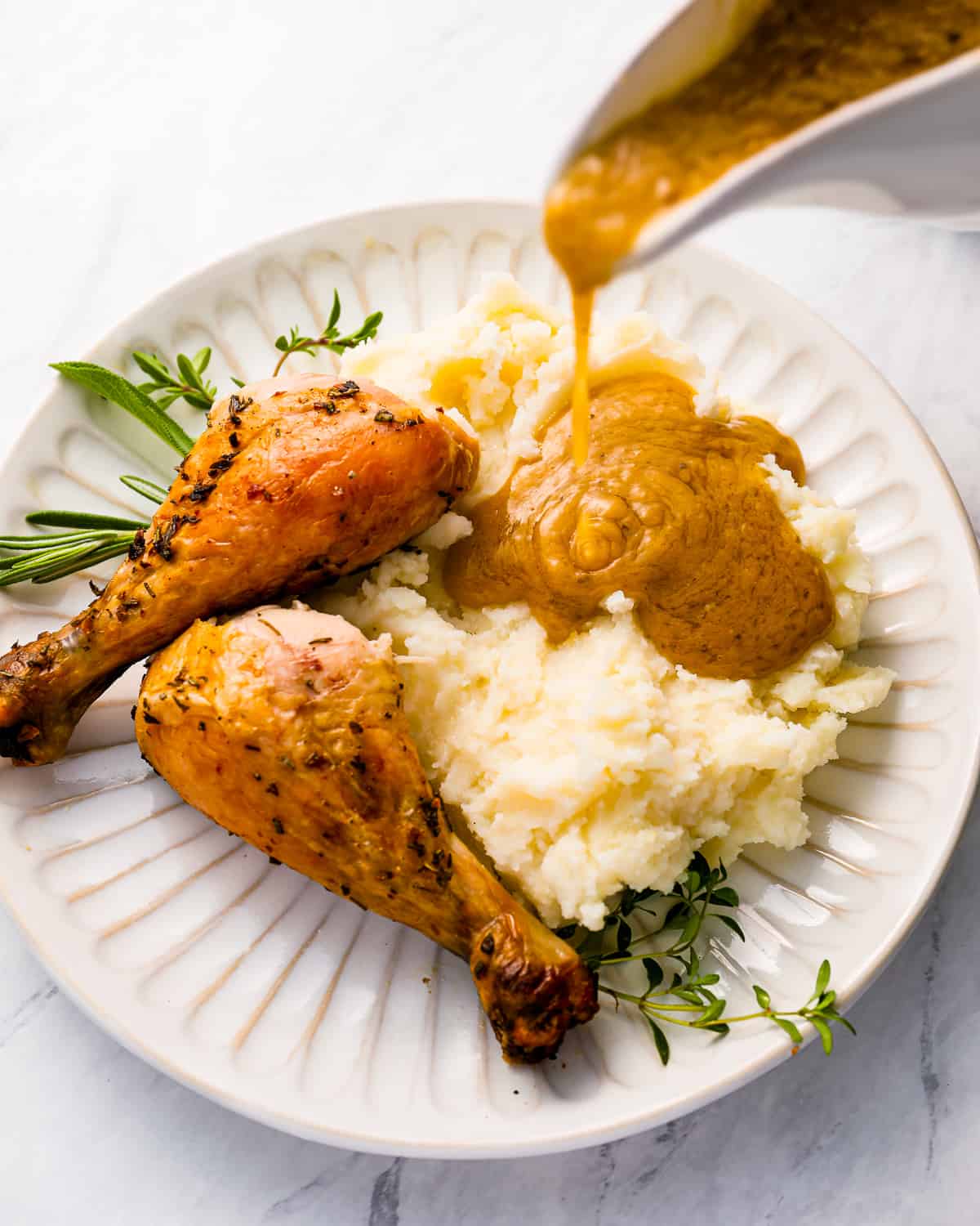 Gravy being poured over Thanksgiving chicken and mashed potatoes.